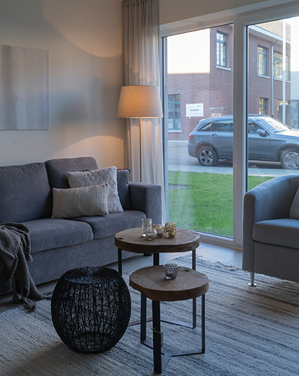 Leefruimte met zitzetel, fauteuil en staande lamp in een assistentie woning van Gaudium in Mol