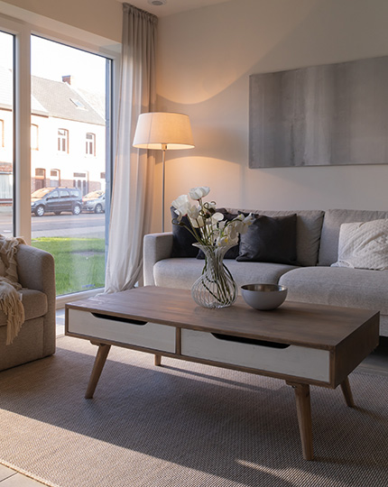 Leefruimte met zitzetel, fauteuil en staande lamp in een assistentie woning van Gaudium in Mol