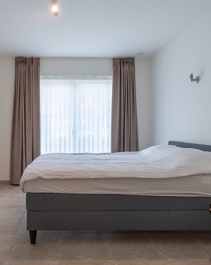 Slaapkamer met bed en venster in een assistentie woning van Gaudium in Mol