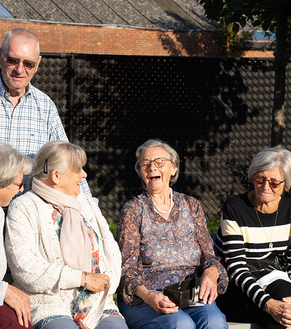 A group of three individuals gathered around a table, focused on a laptop in front of them.